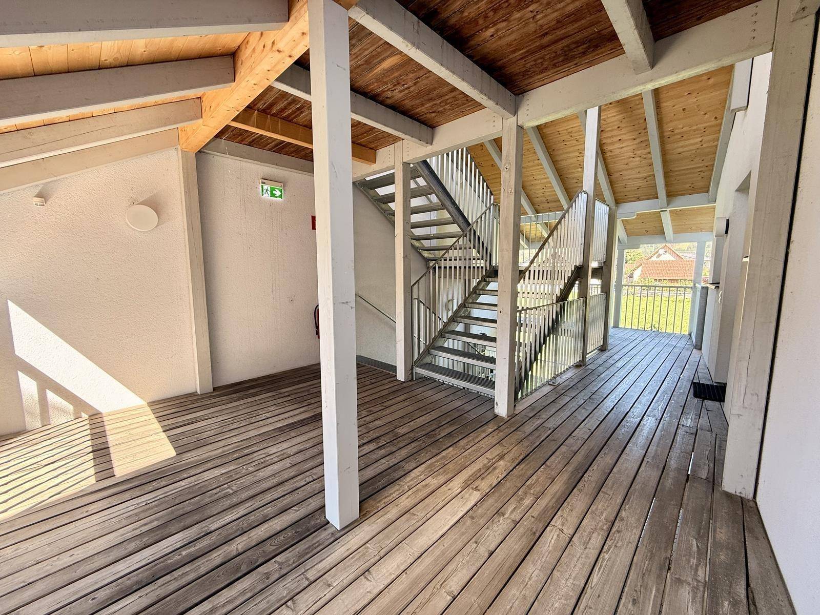 Geräumiger Gemeinschaftsflur mit Holzboden und einer Treppe, die zu den oberen Etagen führt.