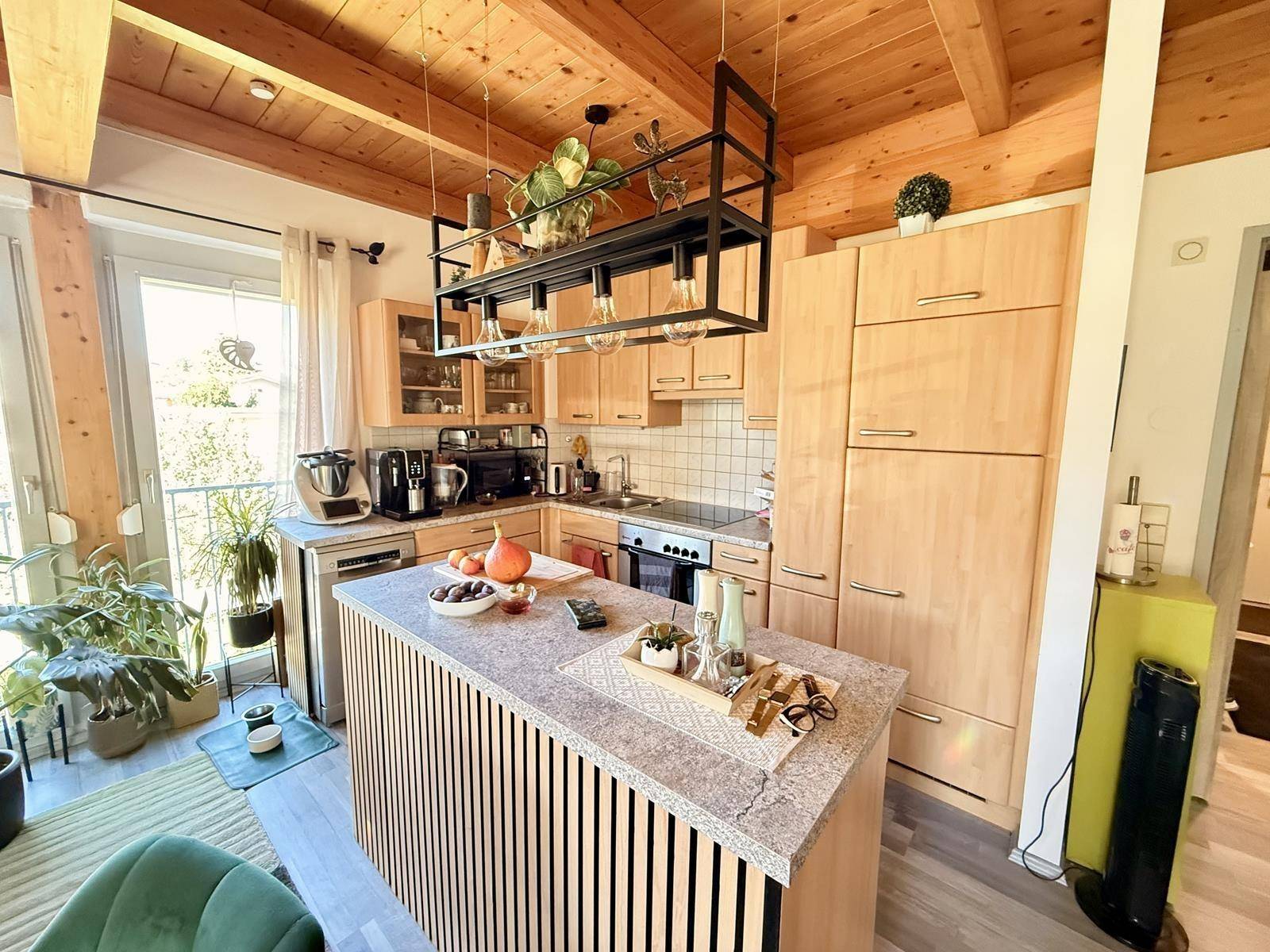 Moderne Küche mit Holzelementen, Kücheninsel und hochwertigen Geräten, mit Zugang zum Außenbereich.
