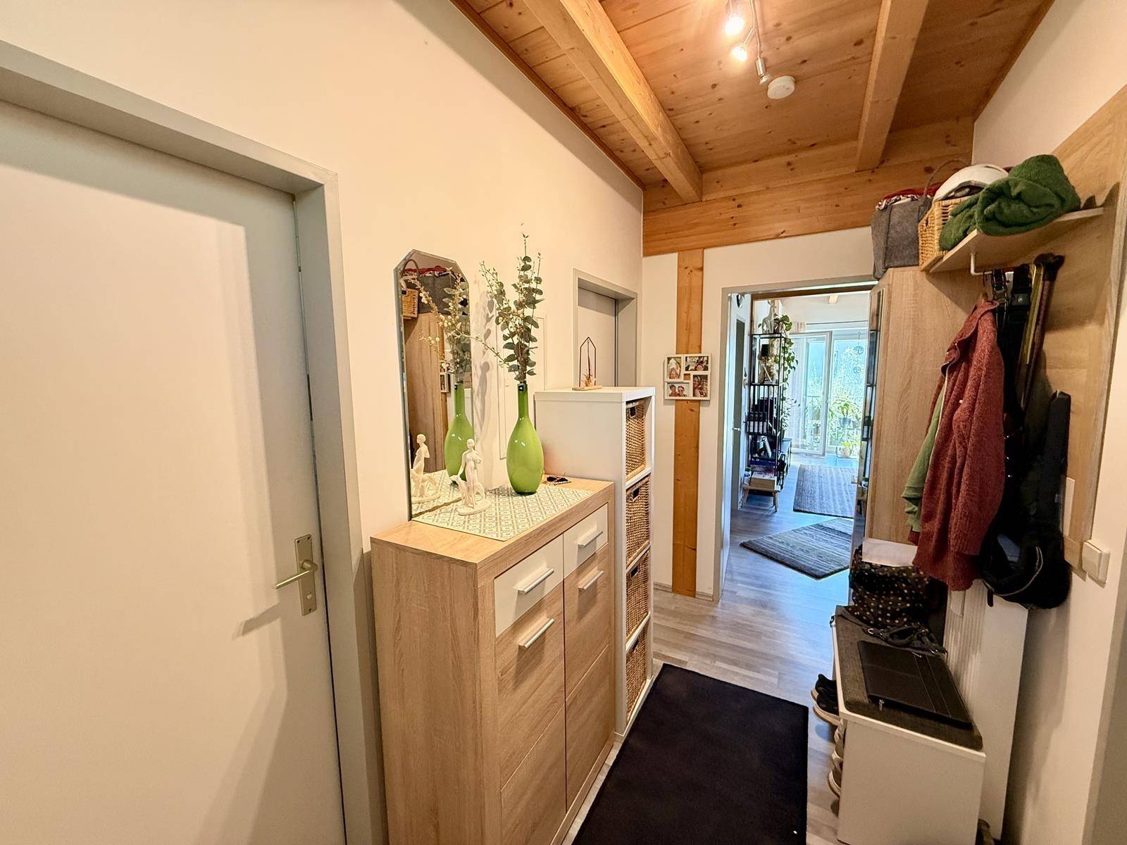 Geräumiger Flur mit Spiegel, Schuhschrank und Blick in den offenen Wohnbereich.