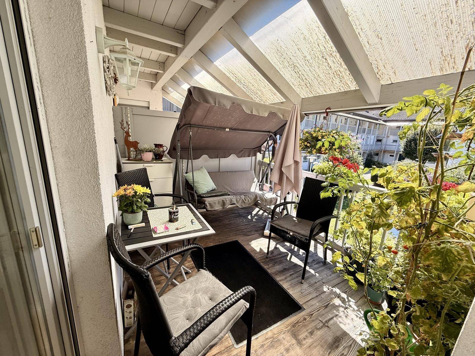 Gemütlicher Balkon mit Schaukelstuhl und Pflanzen, ideal zum Entspannen mit Blick auf den Hof.