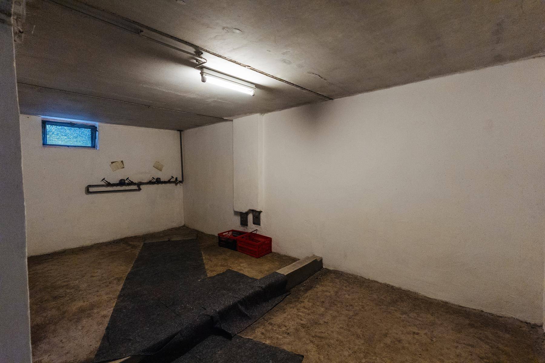 Kellerraum mit Betonboden und -decke, einem kleinen Fenster und einfacher Beleuchtung.