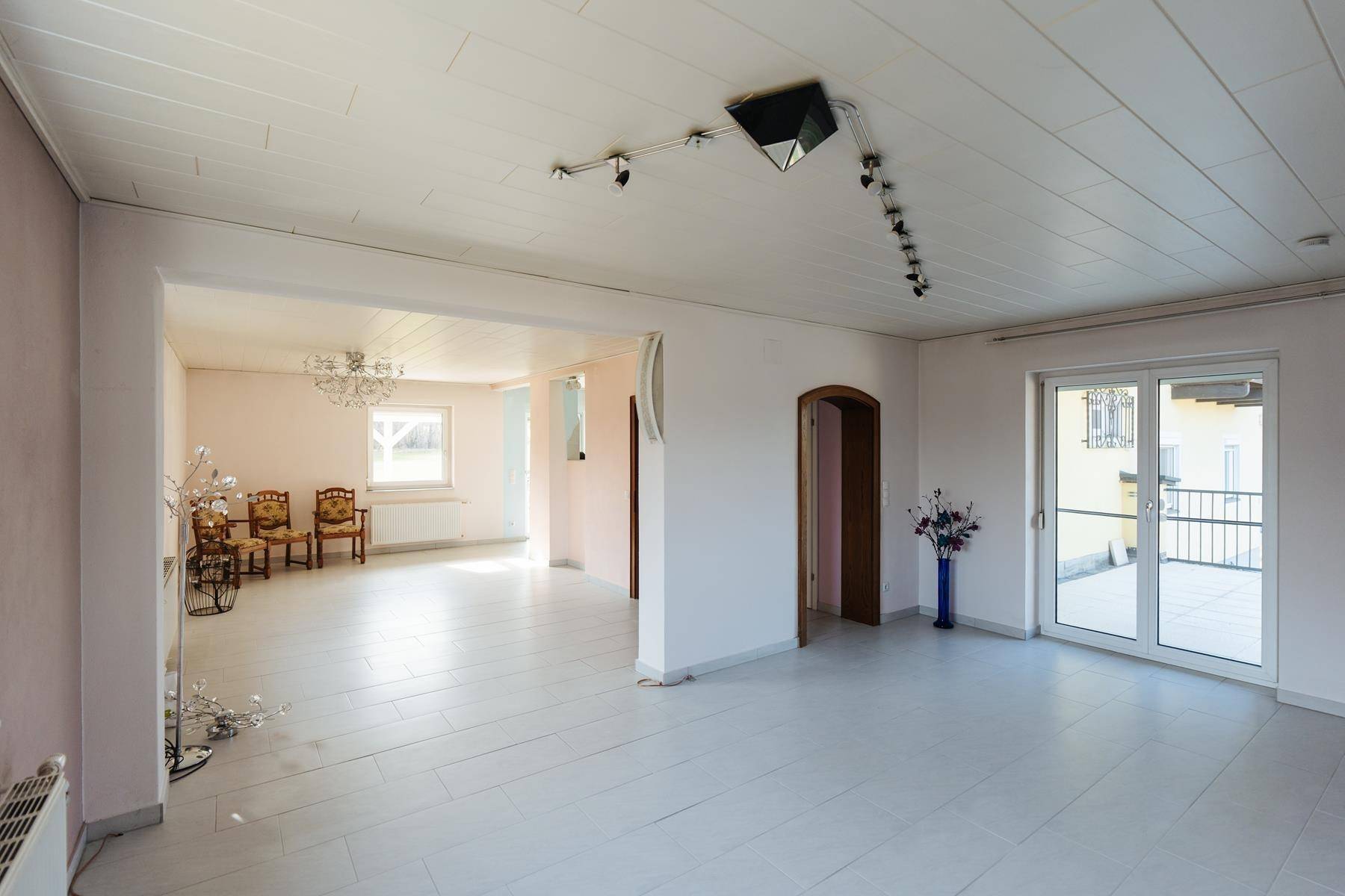 Großer, offener Wohnbereich mit Fliesenboden und Zugang zur Terrasse.