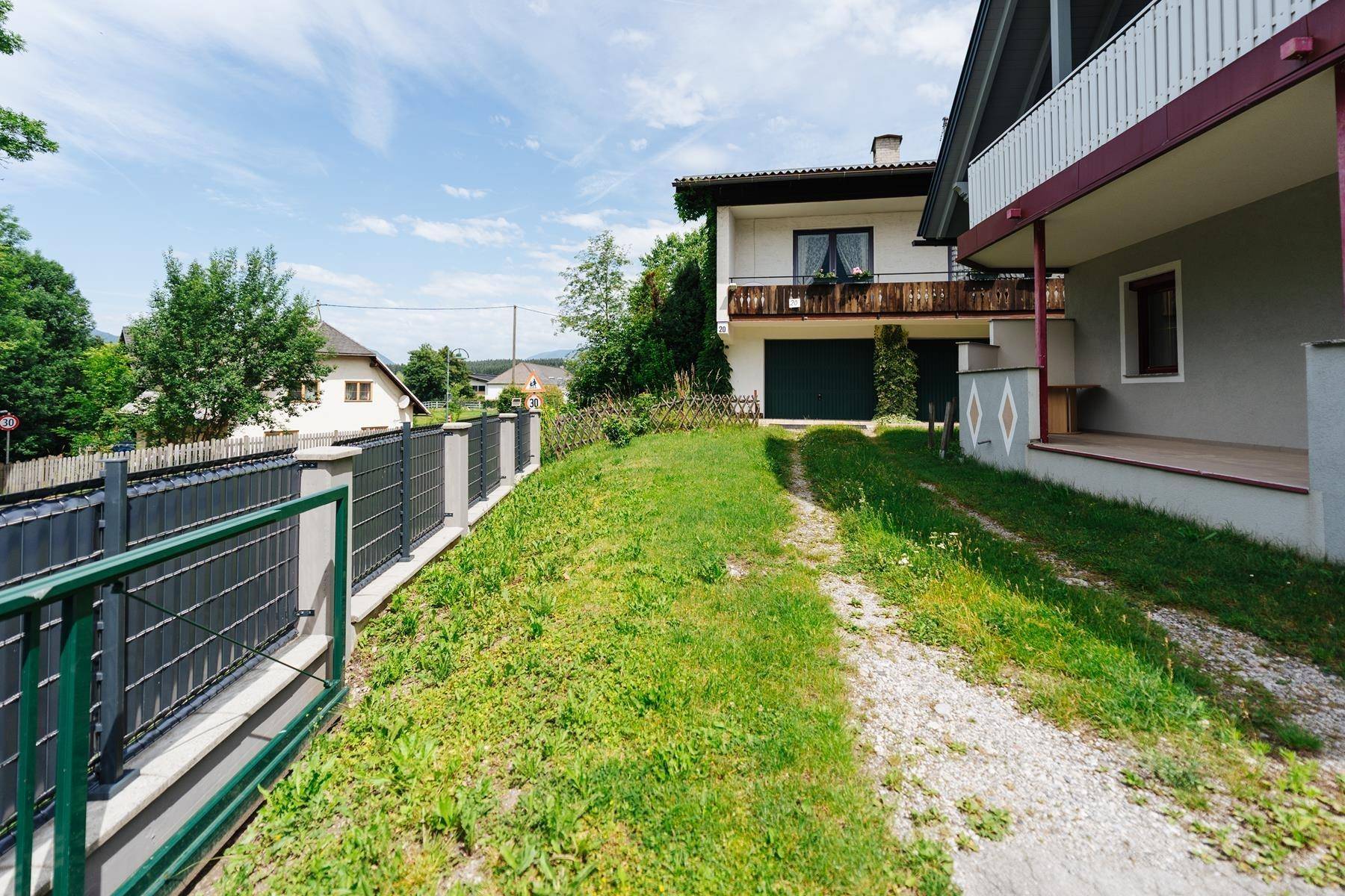 Zufahrt zum Haus mit angrenzendem Garten und Blick auf die Nachbarschaft.