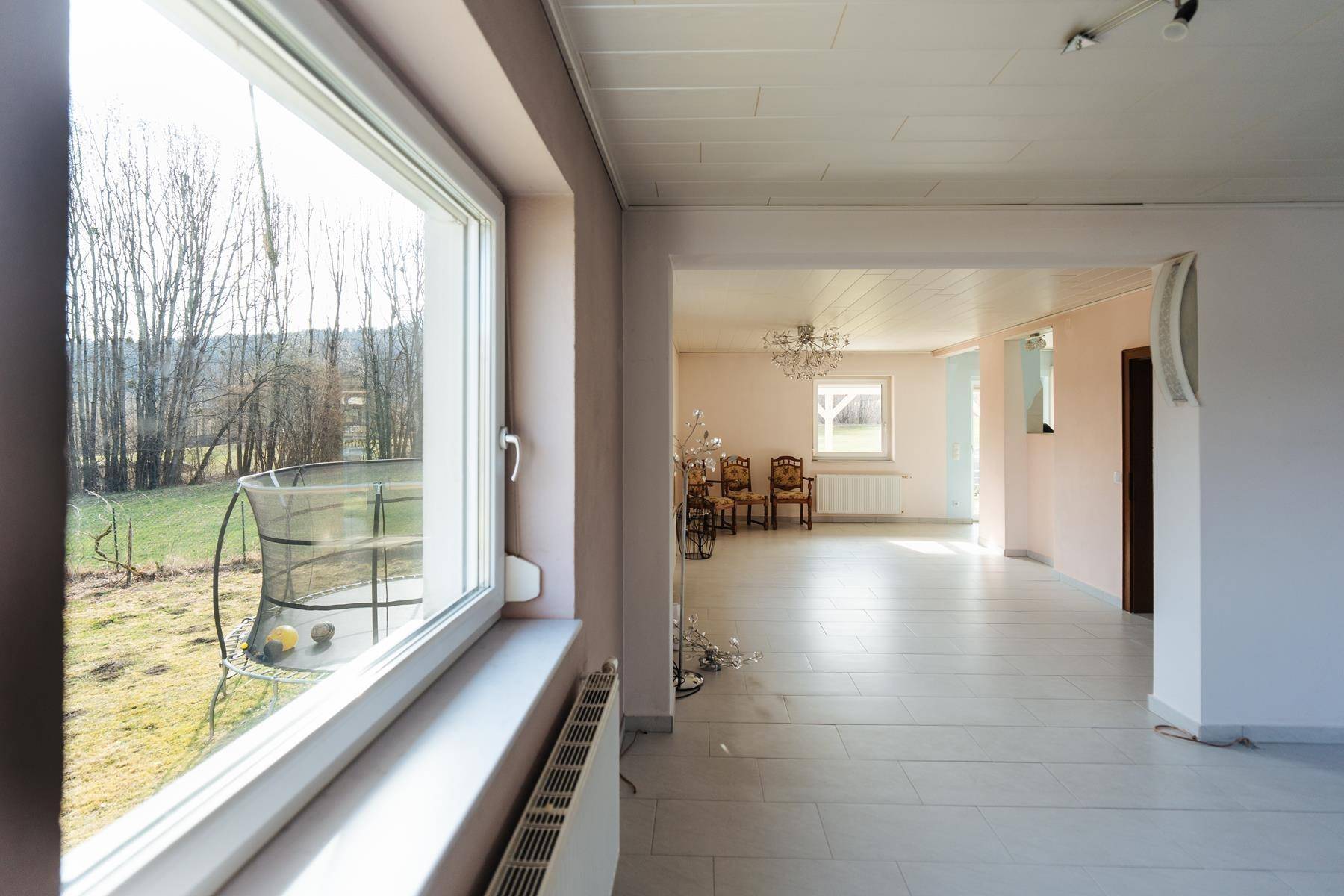 Heller Wohnbereich mit großem Fenster und Blick auf den Garten und die Landschaft.