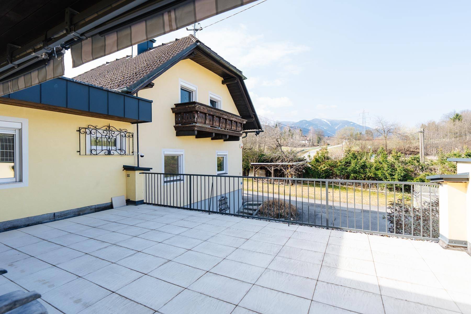 Geräumige Terrasse mit Fliesenboden, Metallgeländer und Bergblick.