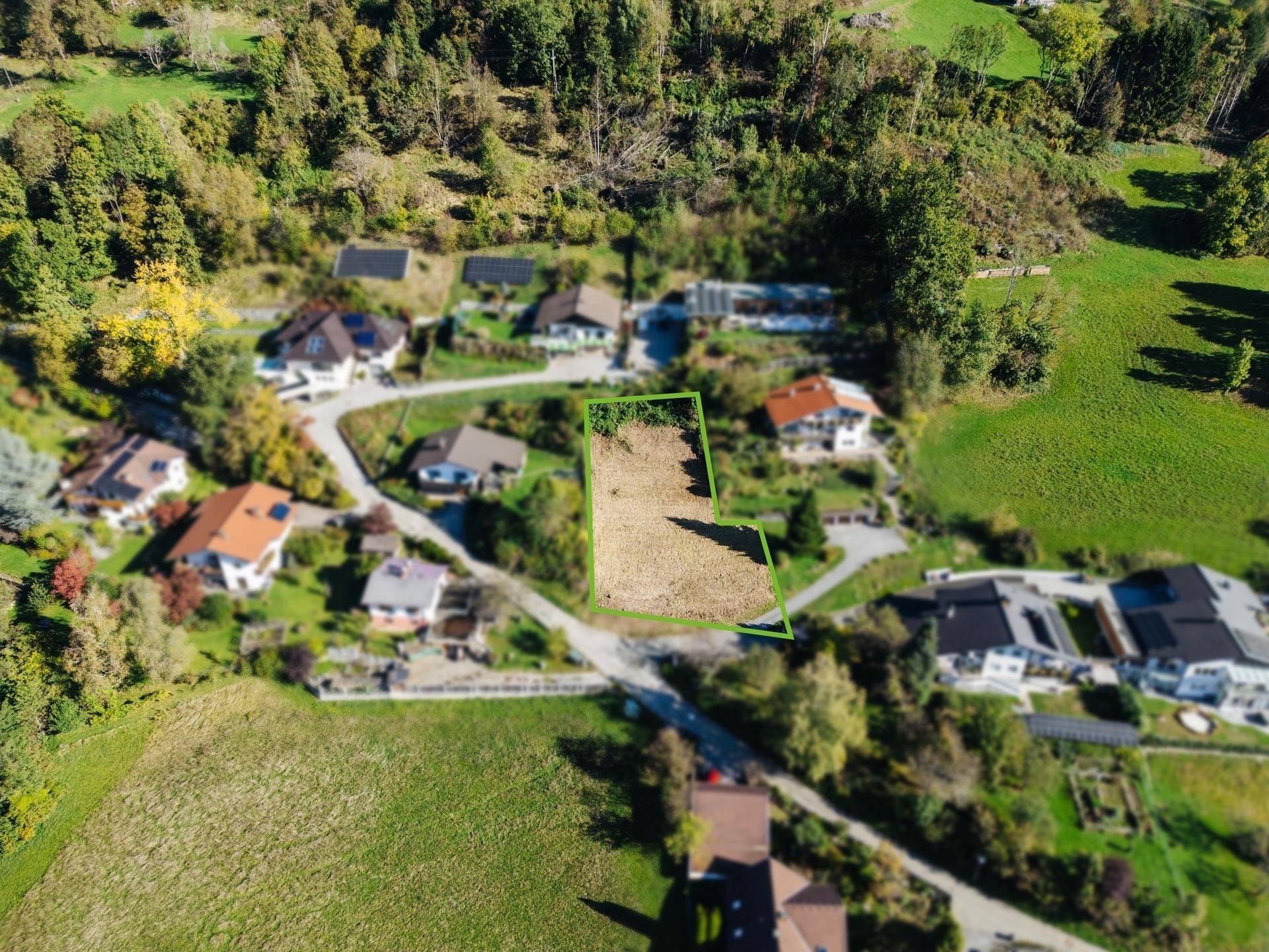Detaillierte Luftaufnahme des Baugrundstücks, umgeben von Einfamilienhäusern und viel Grün.