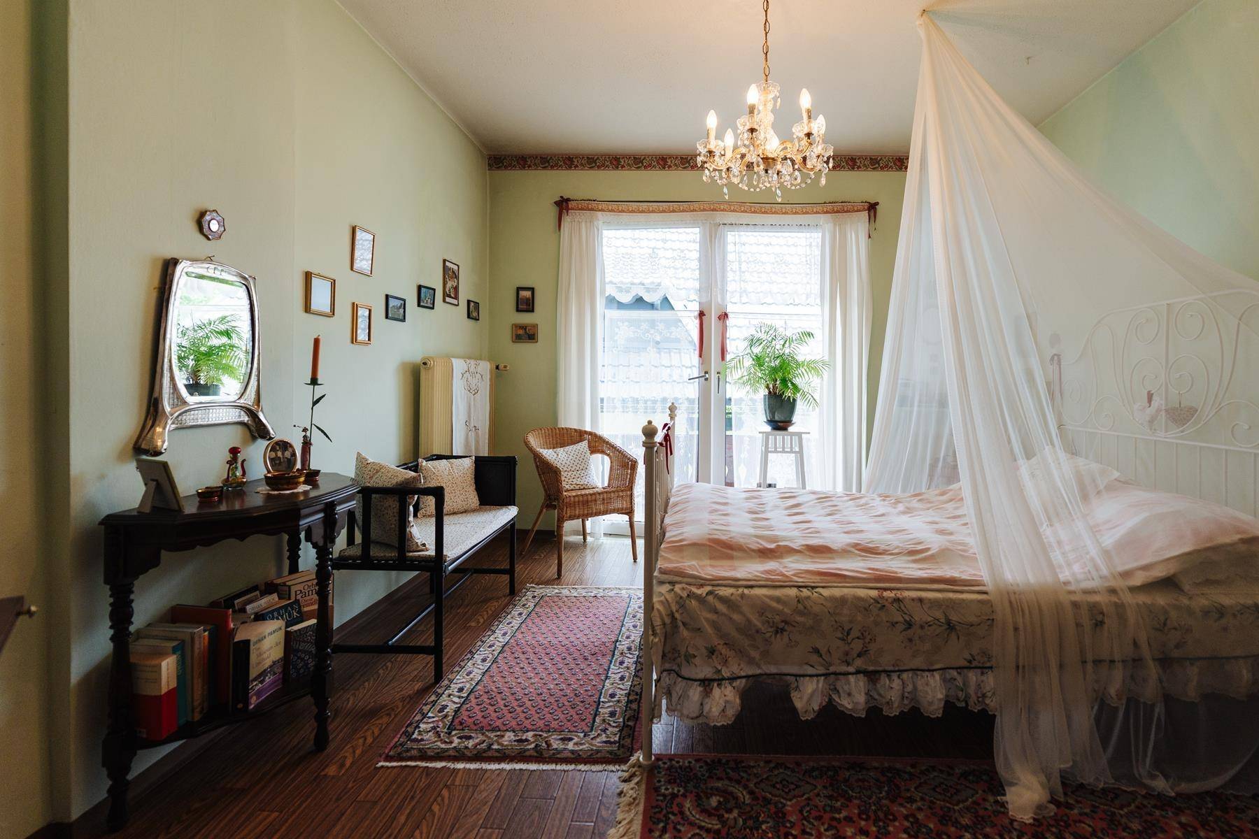 Helles Schlafzimmer mit Himmelbett, traditionellen Möbeln und Zugang zum Balkon.
