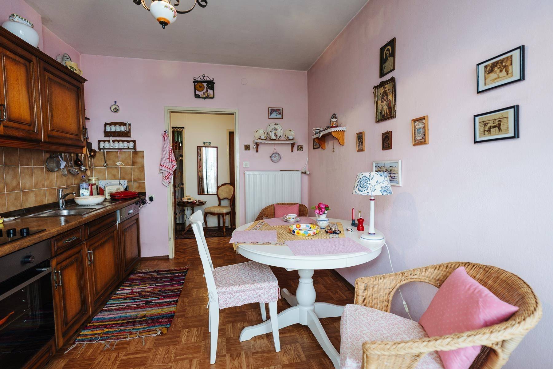 Traditionelle Küche mit Holzeinbauten, Essbereich und rosa Wänden.