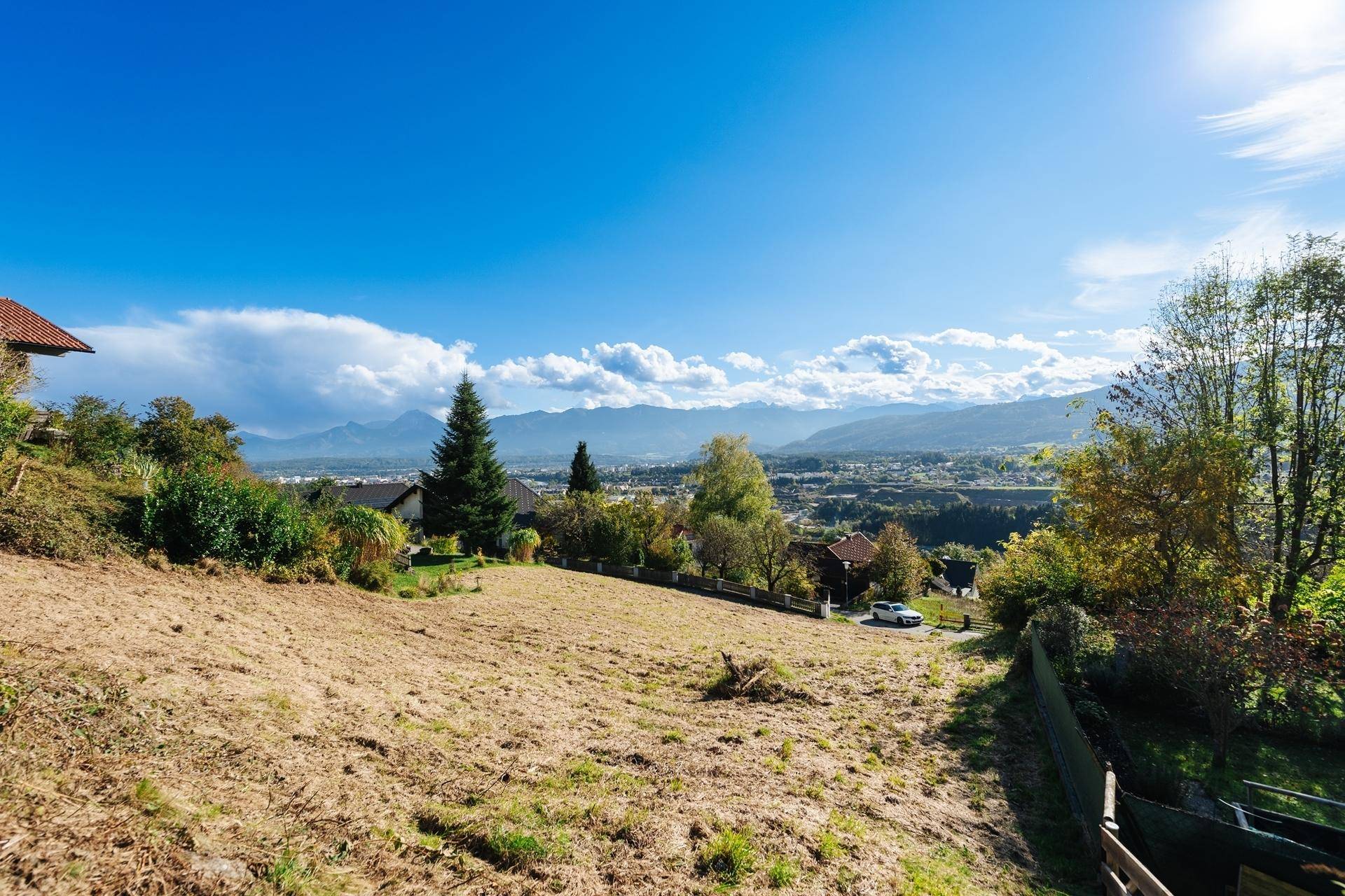 Weitläufiger Blick vom Baugrundstück über die Landschaft bis zur Stadt und den fernen Bergen.