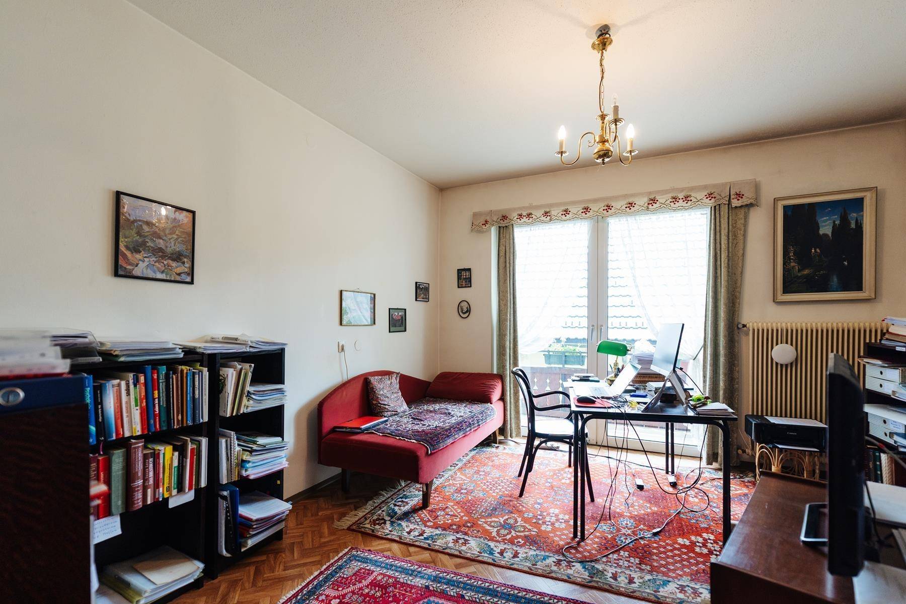 Arbeitszimmer mit Schreibtisch, Bücherregal und rotem Sofa, traditionell eingerichtet.
