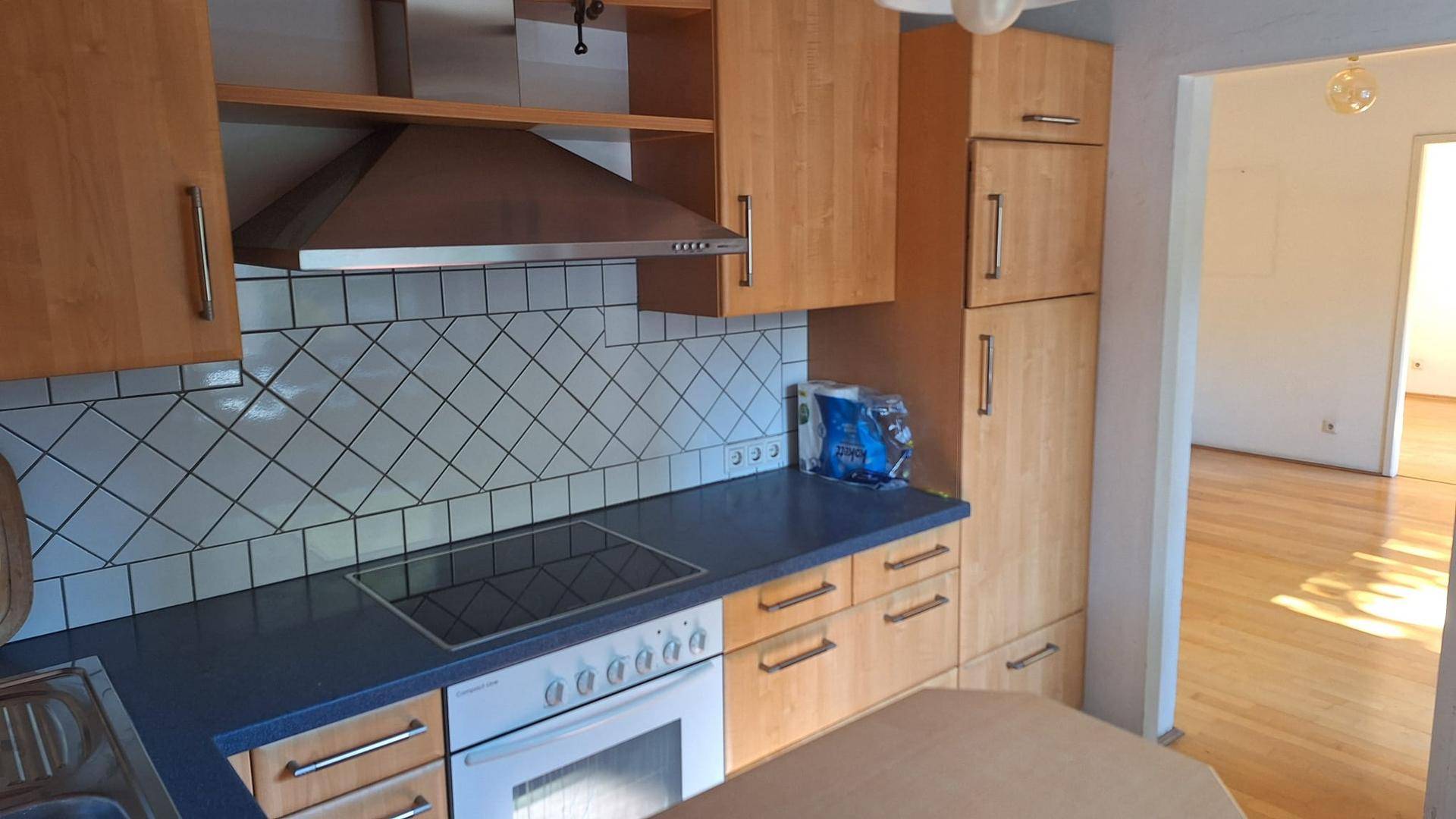 Einbauküche mit Holzschränken, dunkler Arbeitsplatte und Kochfeld.