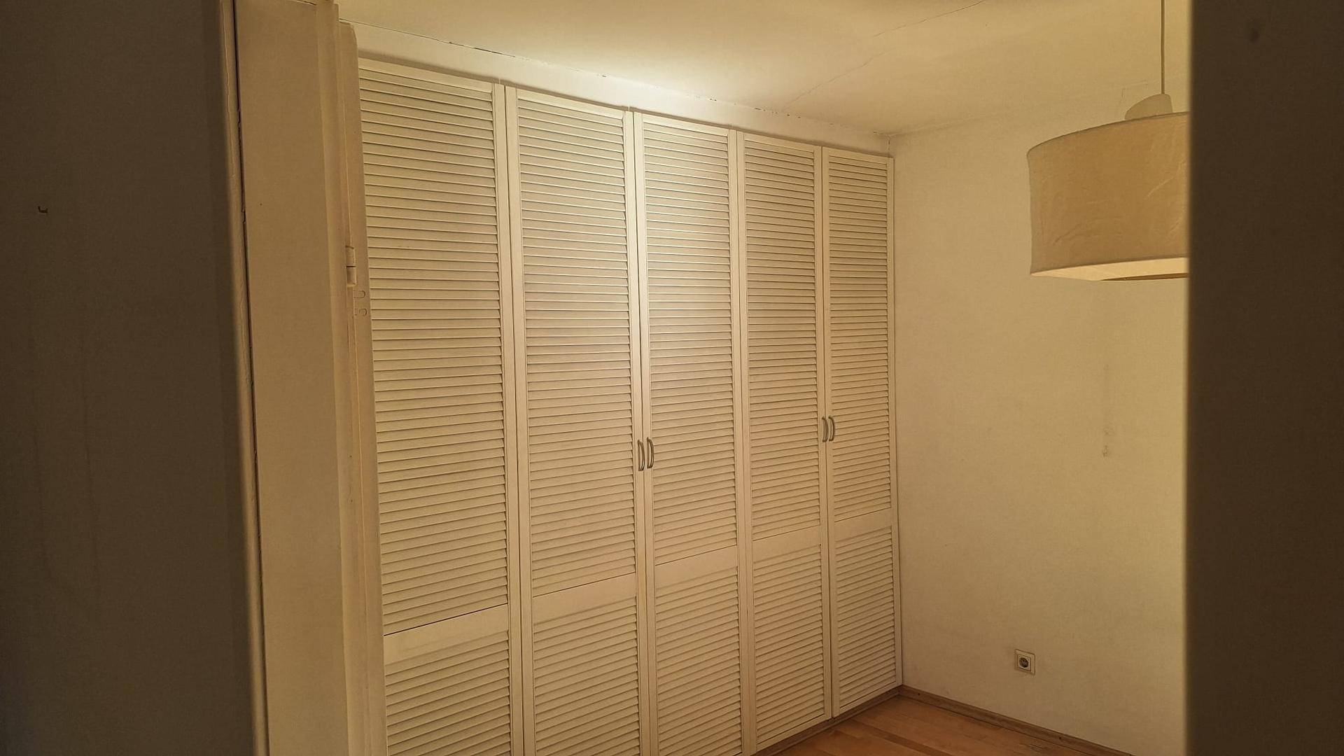 Schlafzimmer mit raumhohen Einbauschränken und Parkettboden.