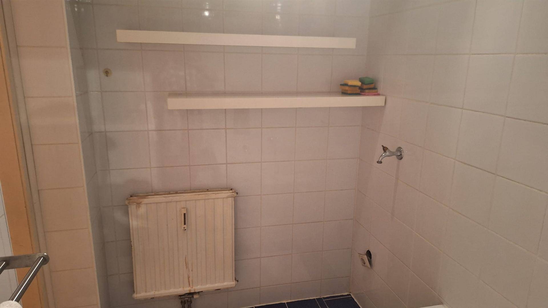 Badezimmerbereich mit weißen Fliesen und Ablageflächen, bereit für die Ausstattung.