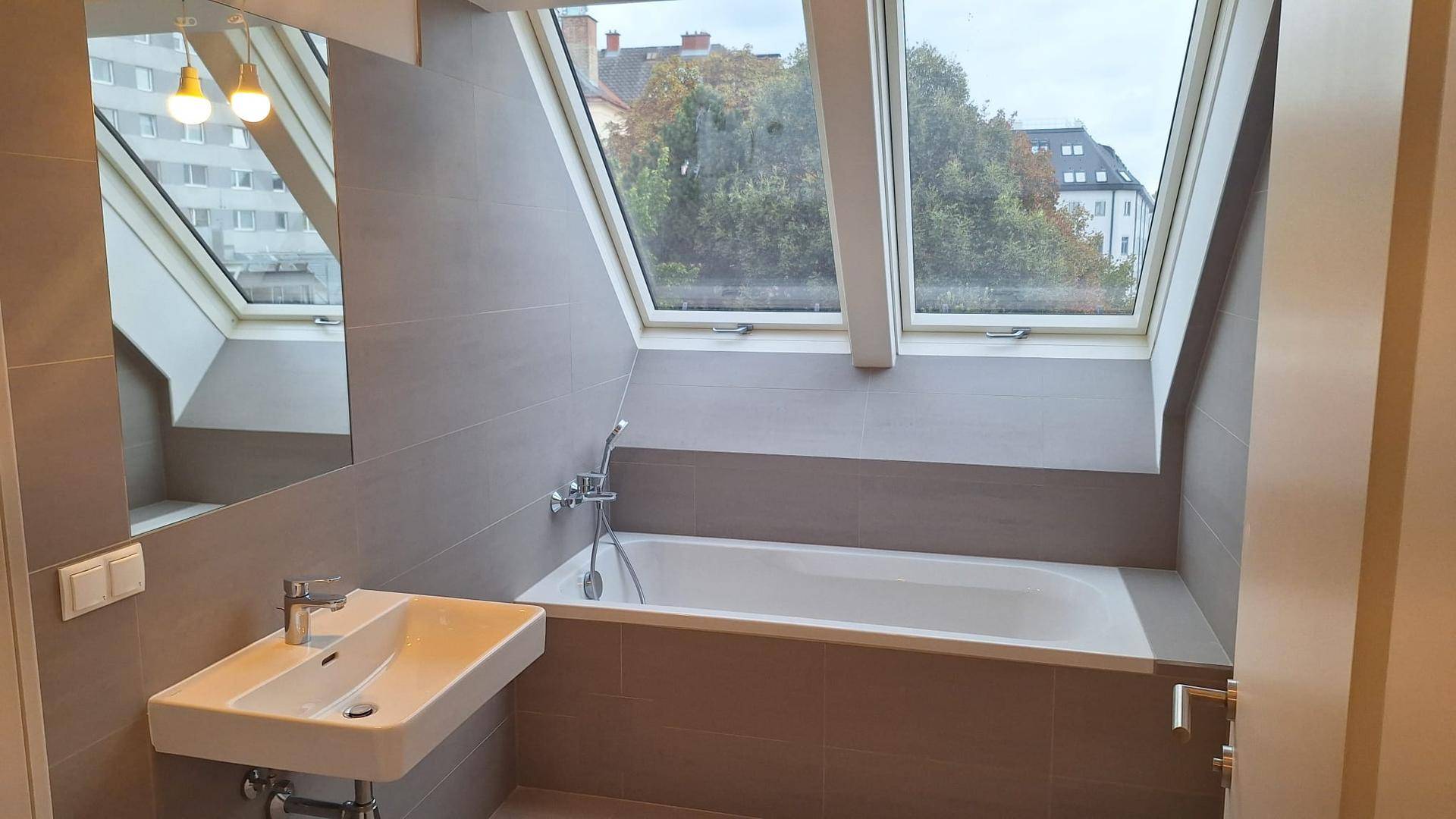 Modernes Badezimmer mit Badewanne, Einzelwaschbecken und Dachfenstern für natürliches Licht.