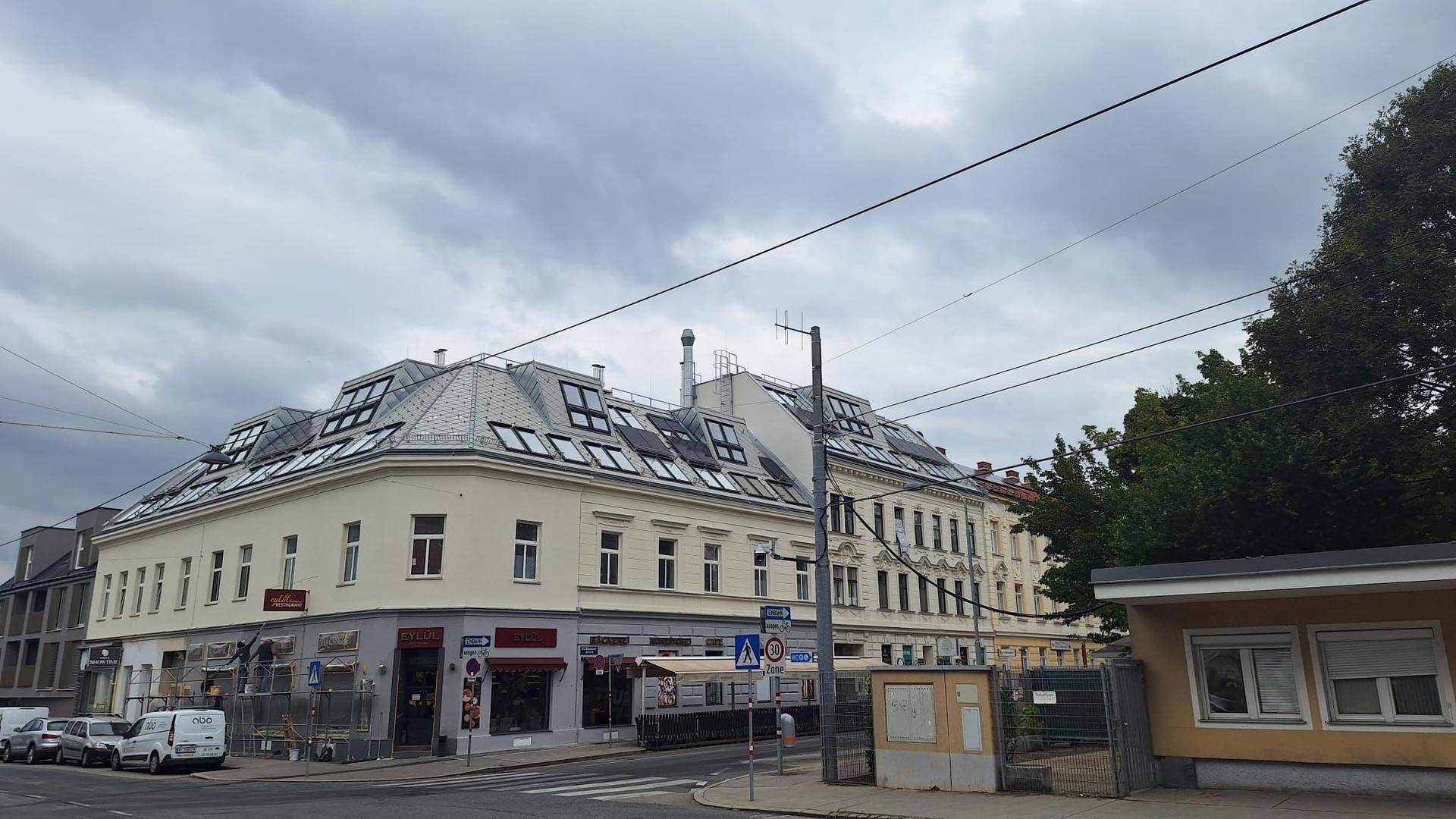 Historisches Gebäude mit modernisiertem Mansarddach und vielen Dachfenstern an einer belebten Straße.