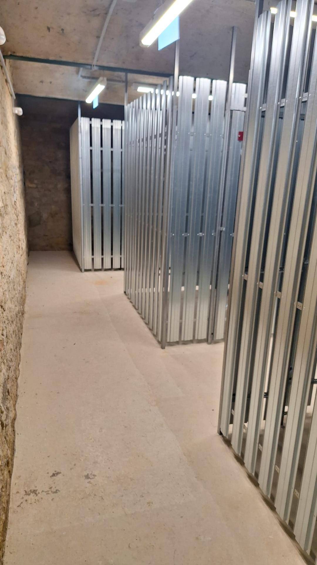 Kellerraum mit individuellen Lagerabteilen aus Metallgittern für zusätzlichen Stauraum.
