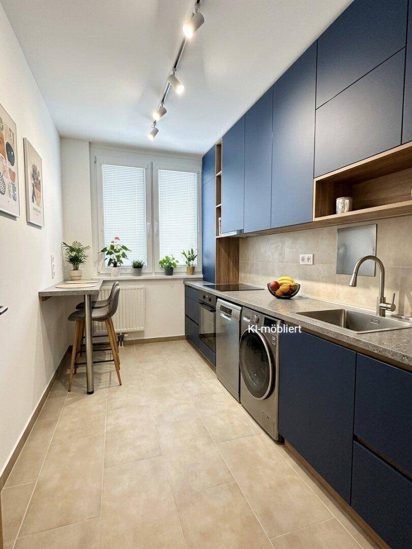 Moderne Küche mit dunkelblauen Schränken, integrierten Geräten und einem kleinen Frühstücksbereich am Fenster.