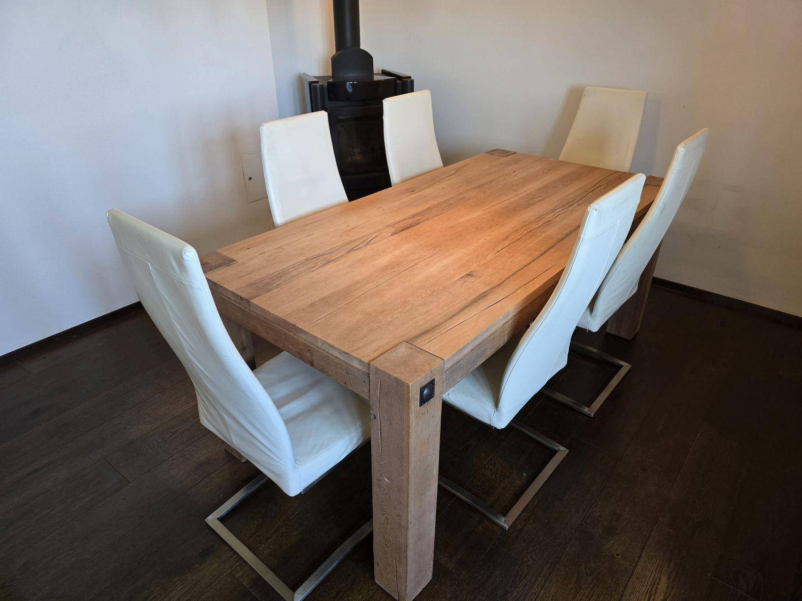 Detailaufnahme des Esstisches aus Massivholz mit modernen, weißen Stühlen im Dachgeschoss.