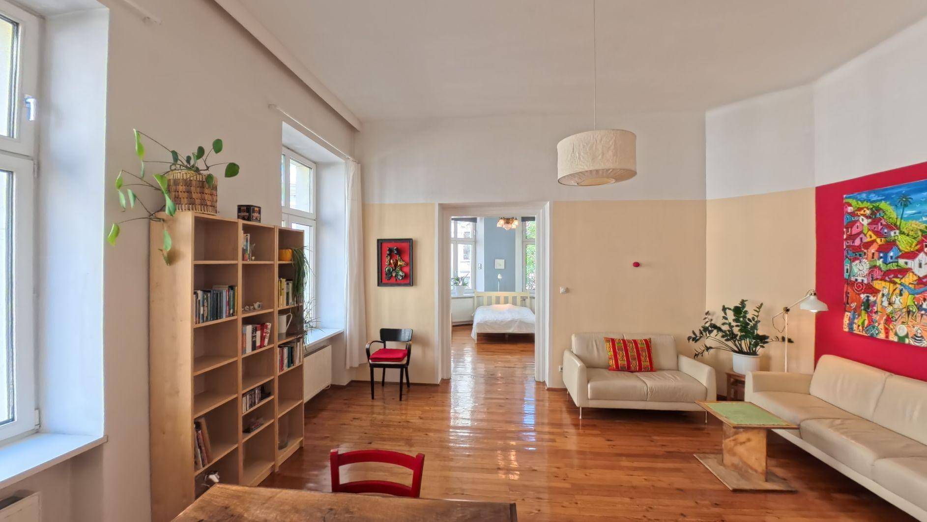 Heller Wohn- und Essbereich mit Holzboden, bequemen Sofas und Blick in ein angrenzendes Schlafzimmer.