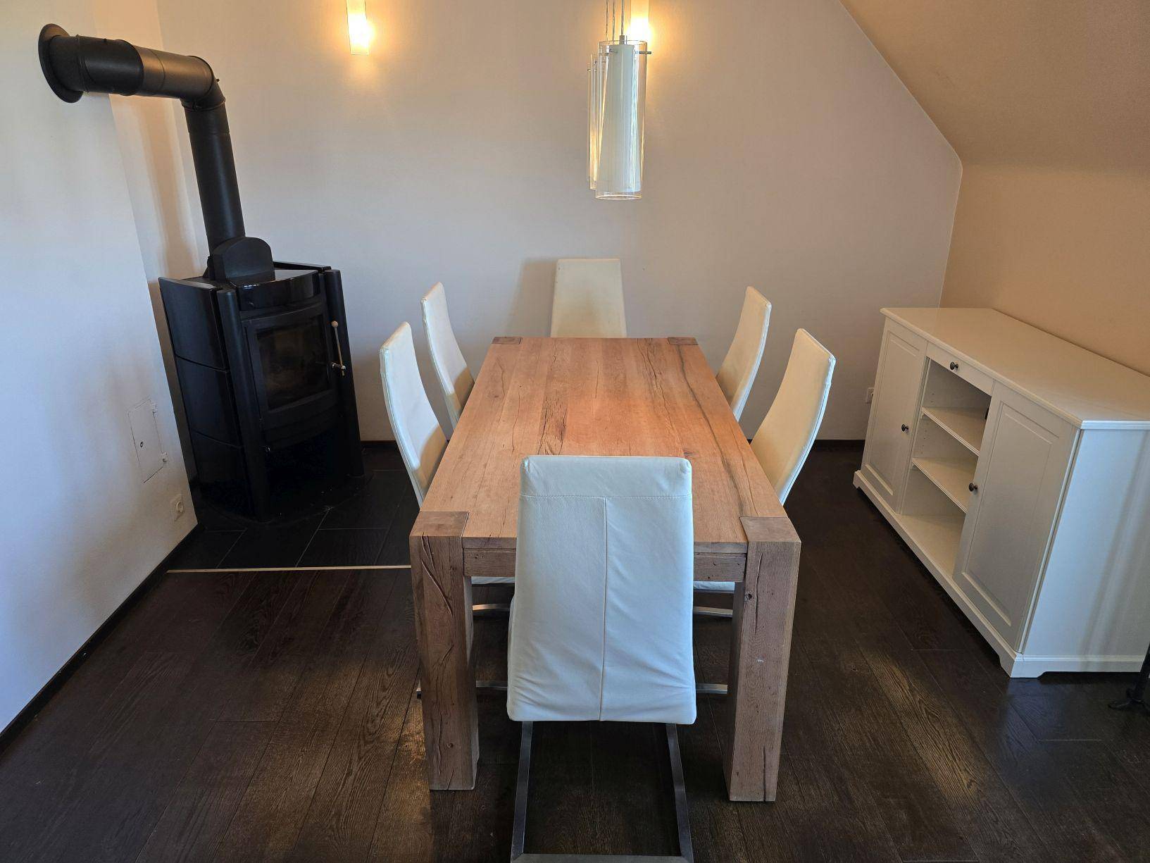 Gemütlicher Essbereich mit Holztisch, modernen Stühlen und einem stilvollen Holzofen.