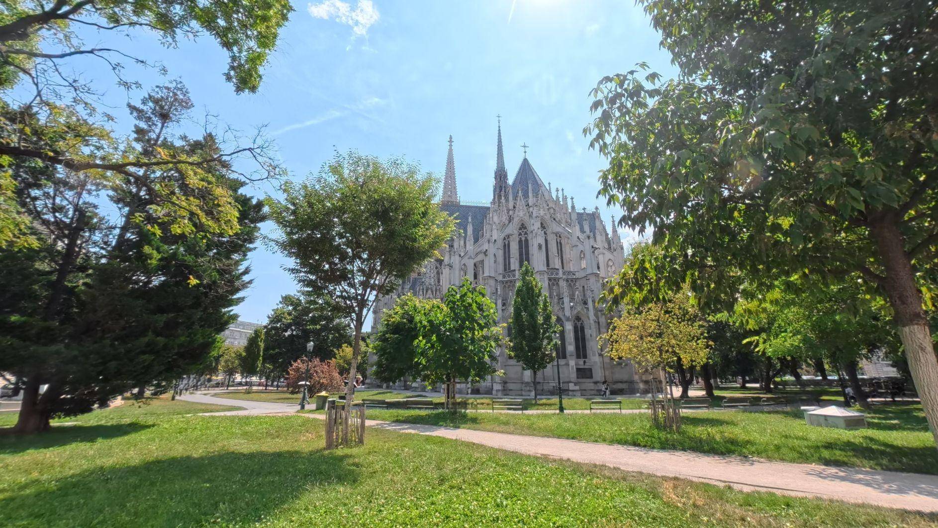 Historisches Kirchengebäude umgeben von grünen Bäumen und einem sonnigen Park.