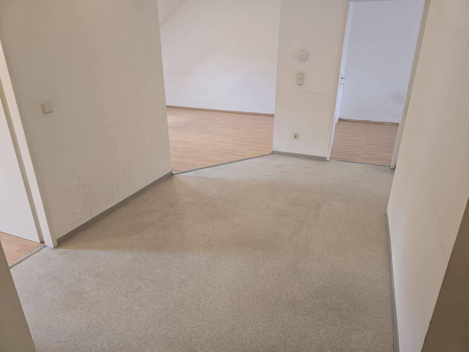 Flur mit Linoleumboden, der zu den angrenzenden Räumen mit Laminatboden führt.