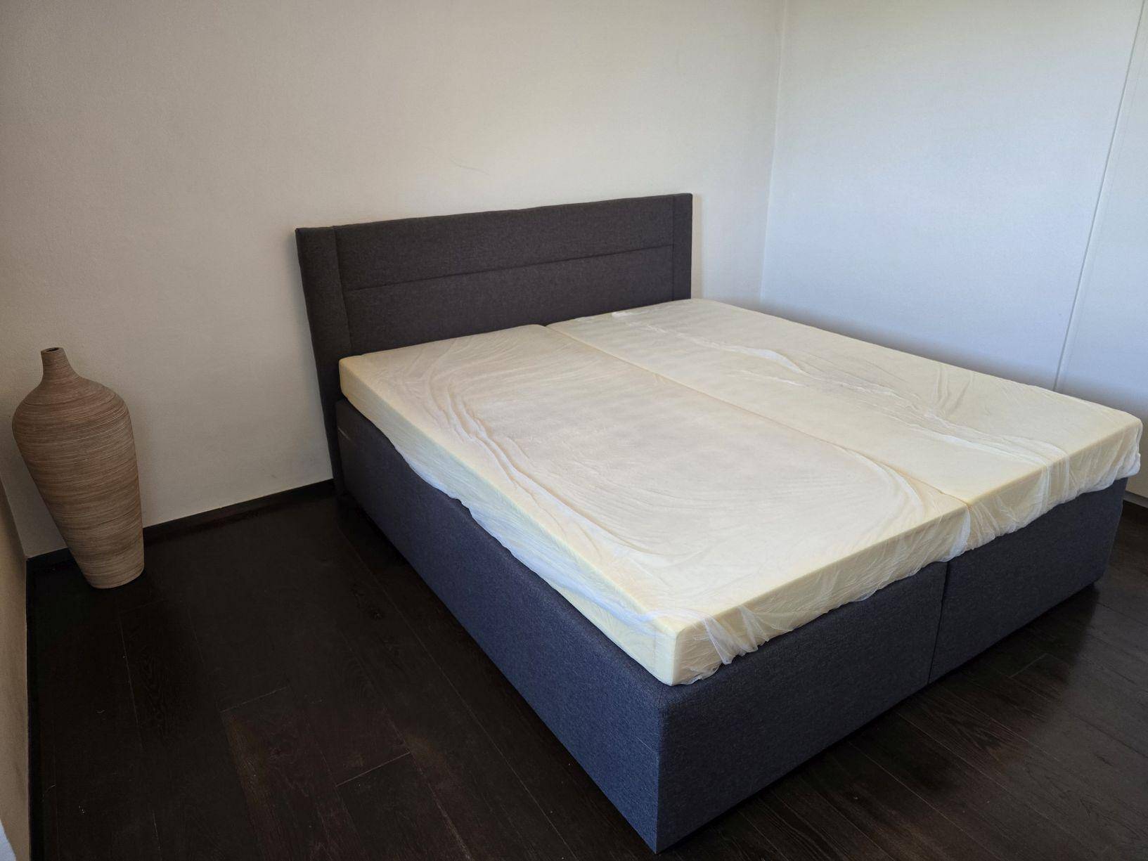 Schlafzimmer mit Doppelbett und dunklem Holzboden in minimalistischem Design.