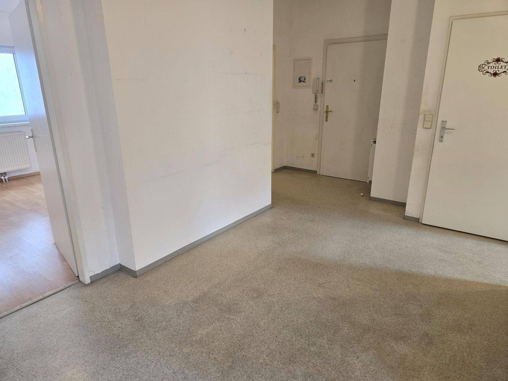 Eingangsbereich mit Linoleumboden und Türen zu verschiedenen Zimmern der Wohnung.