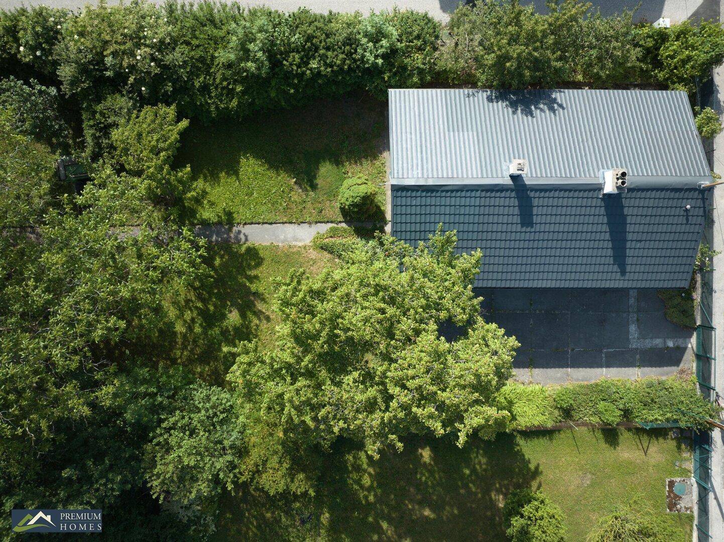 Vogelperspektive des Hauses mit Satteldach und dem weitläufigen, grünen Gartenbereich mit Bäumen.