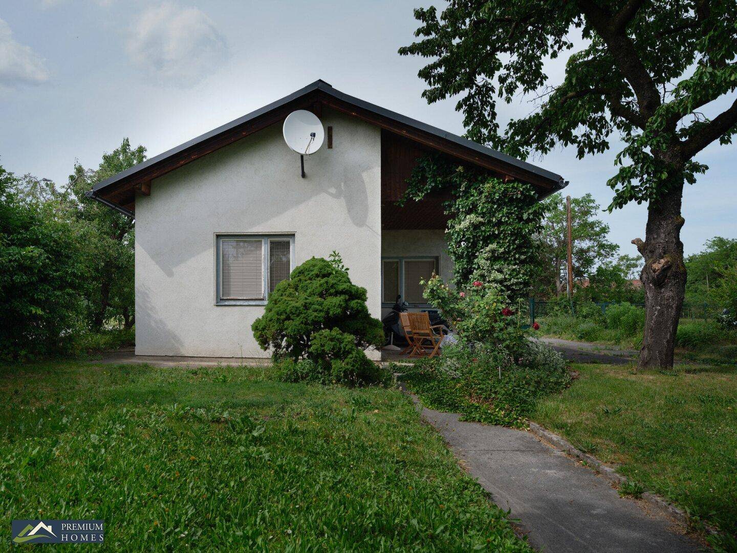 Das Einfamilienhaus mit weißer Fassade und Satteldach, umgeben von einem großen, grünen Garten.