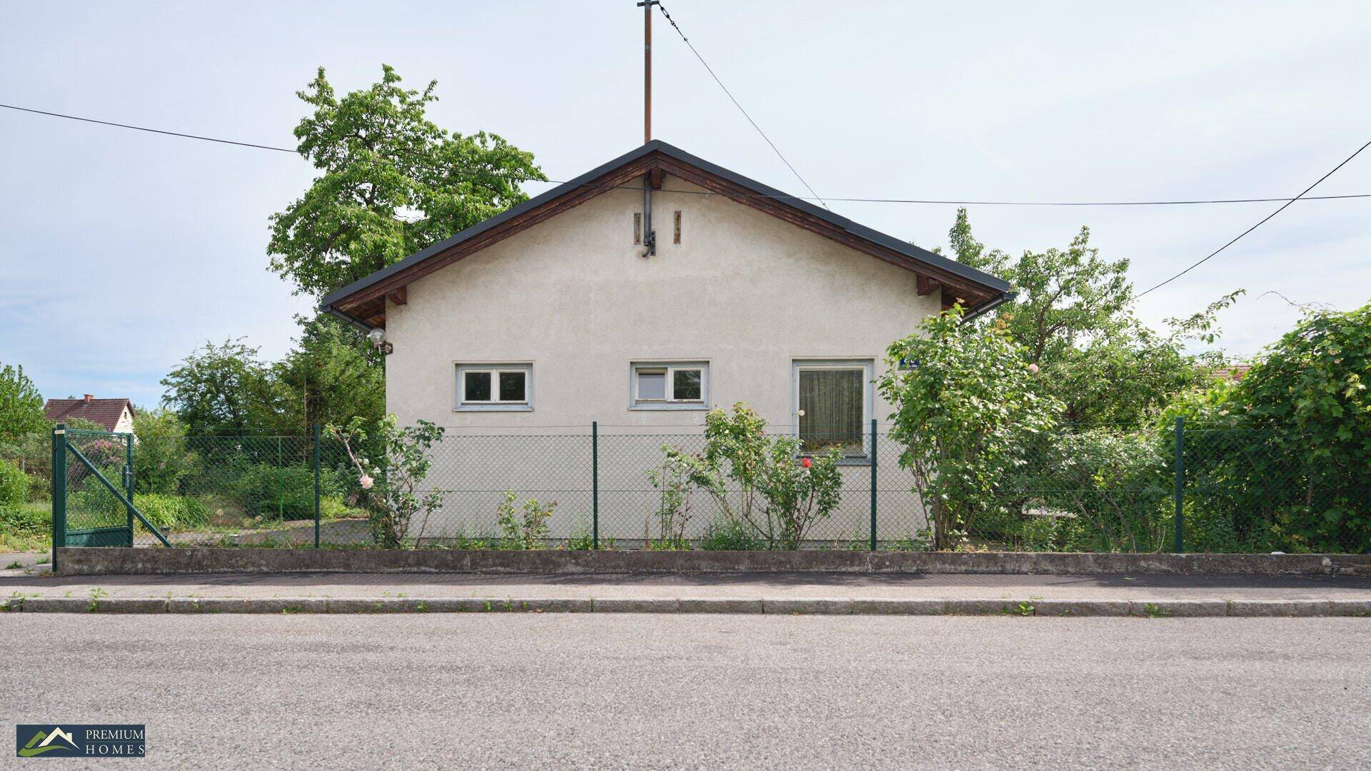Die Vorderseite des Einfamilienhauses mit weißer Fassade und Fenstern, direkt an der Straße gelegen.