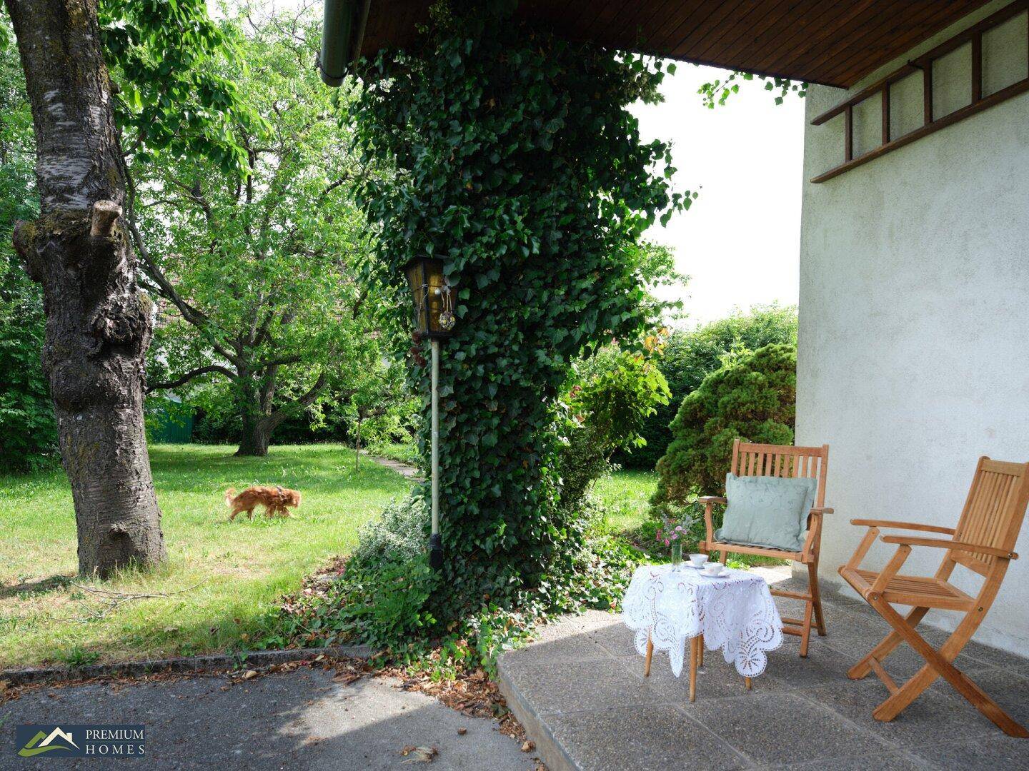 Gemütlicher Sitzbereich auf der Terrasse mit Holzmöbeln und Blick auf den weitläufigen Garten.