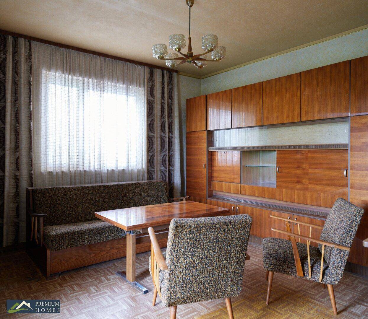 Essbereich mit Holztisch, Stühlen und Sofa, ergänzt durch eine große Holzschrankwand.