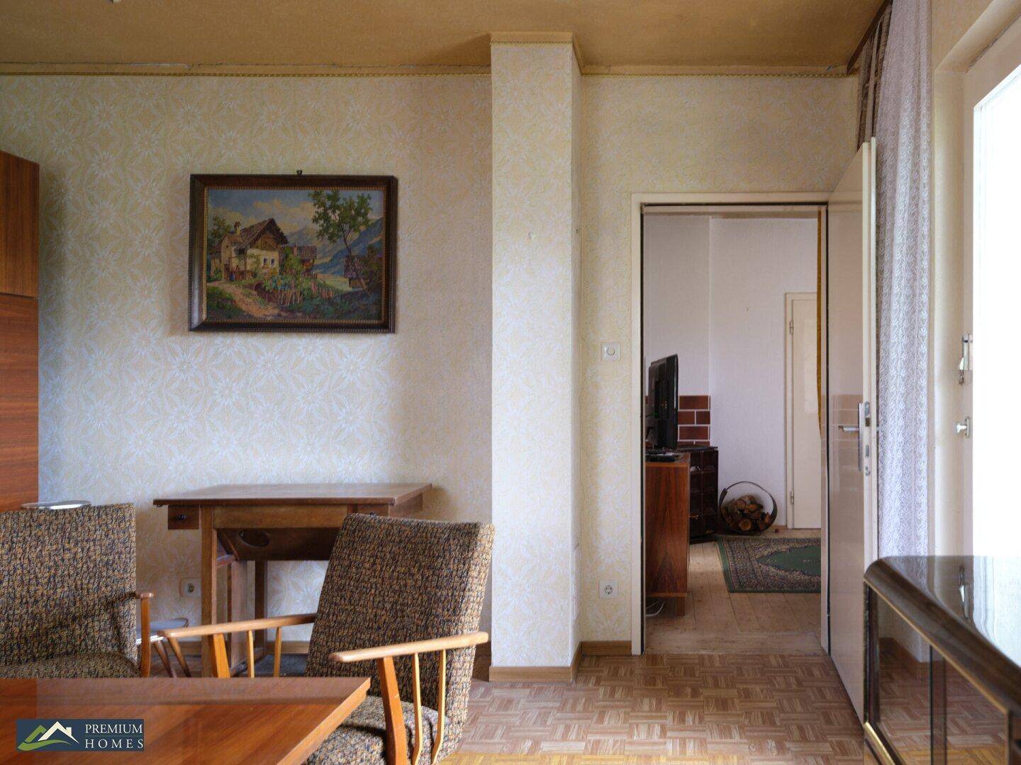 Essbereich mit Stühlen und einem Gemälde an der Wand, mit Blick in einen angrenzenden Raum.