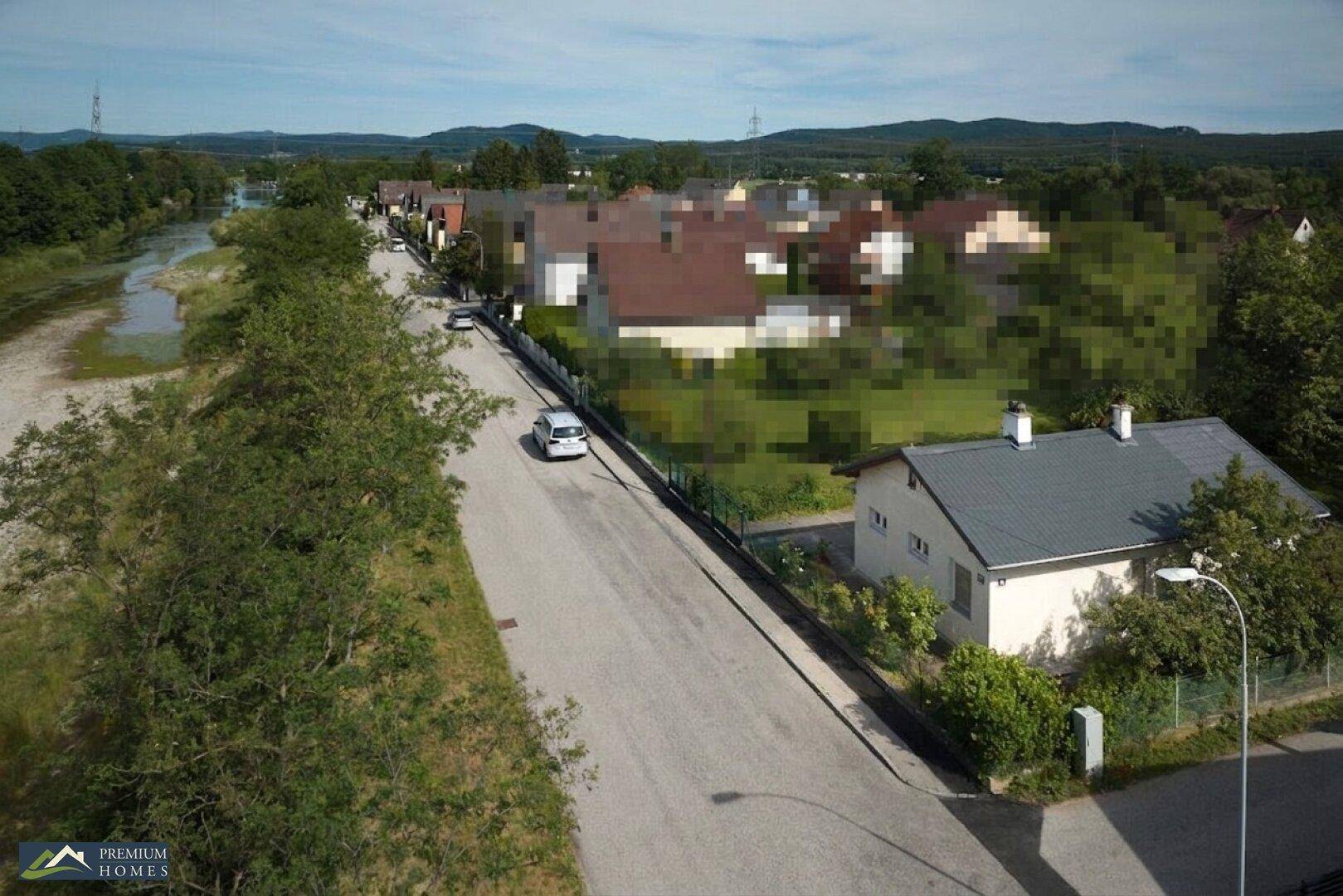 Luftaufnahme des Hauses an einer ruhigen Straße, angrenzend an einen Fluss und umgeben von viel Grün.