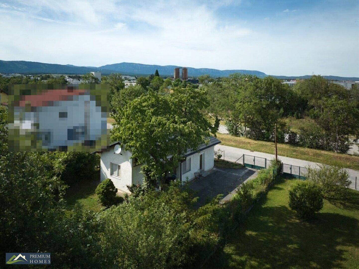 Luftaufnahme des Hauses mit großem Garten und einer kleinen Terrasse, umgeben von Bäumen.