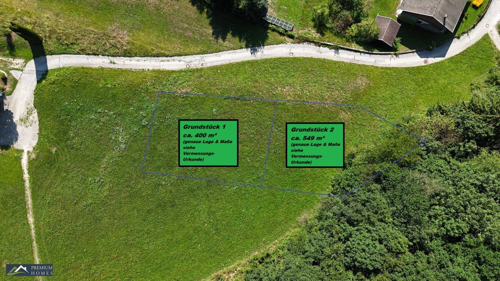 Luftaufnahme eines grünen Grundstücks mit markierten Parzellen und angrenzender Straße.