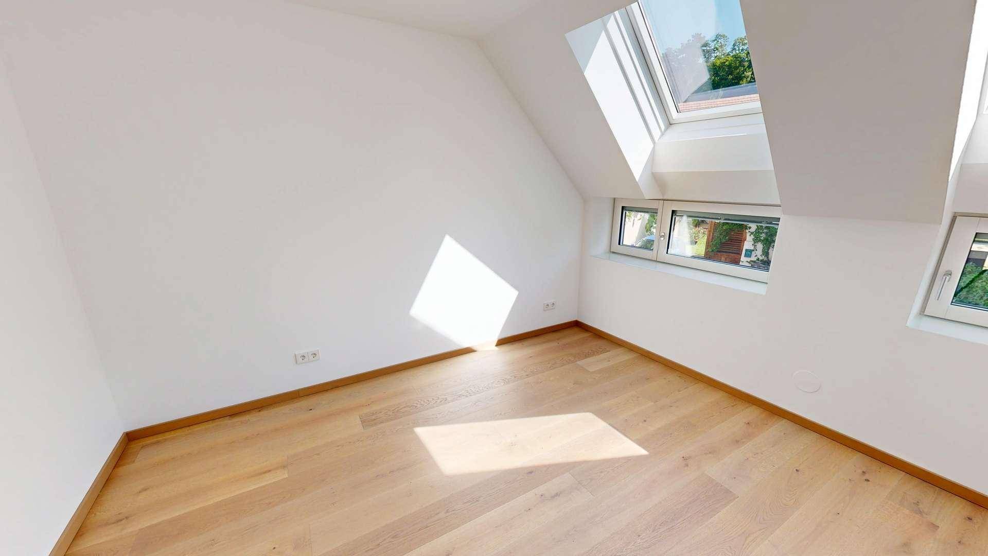 Helles Schlafzimmer im Dachgeschoss mit Holzboden, Dachfenstern und viel Tageslicht.