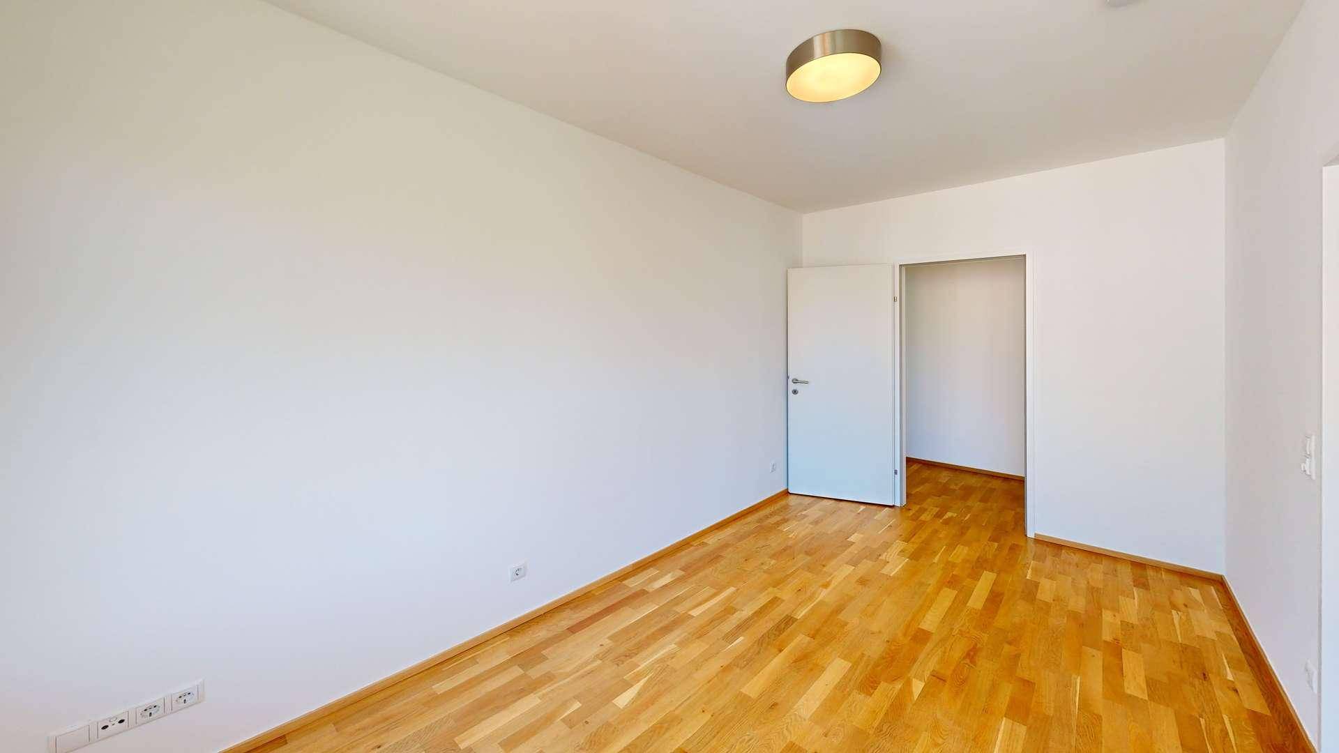 Leeres Zimmer mit hellem Parkettboden und weißen Wänden, bereit zur individuellen Gestaltung.