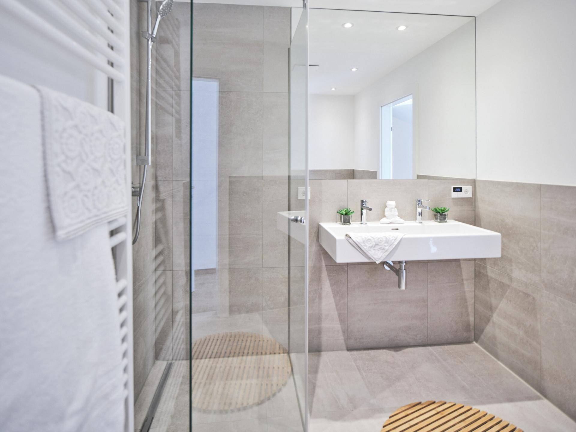 Zeitgemäßes Badezimmer mit begehbarer Dusche, Einzelwaschbecken und großem Spiegel.