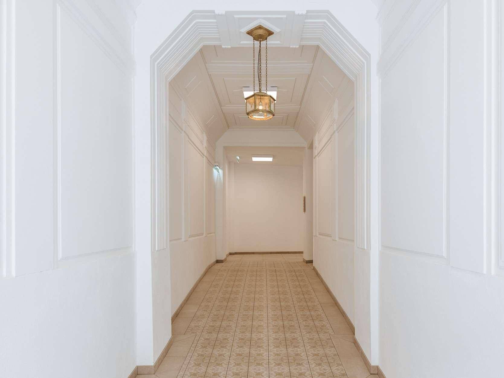 Eleganter Flur mit gemustertem Fliesenboden, dekorativen Wandpaneelen und einer klassischen Hängelampe.