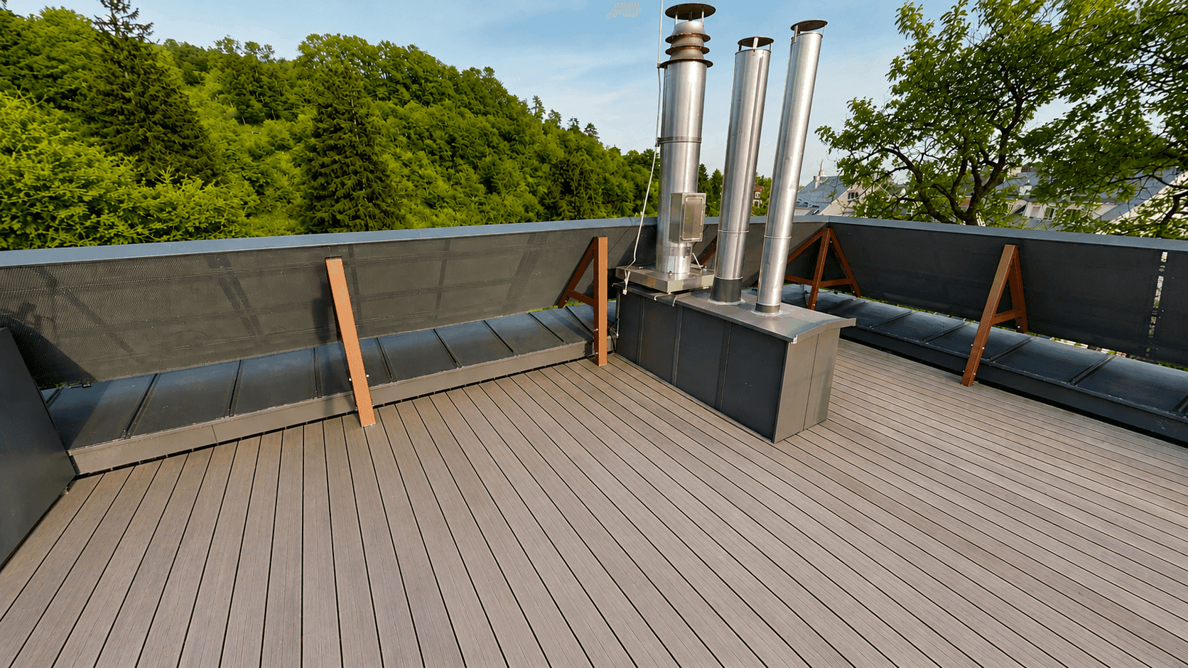 Weitläufige Dachterrasse mit modernem Holzboden und Blick auf die umliegende Hügellandschaft.