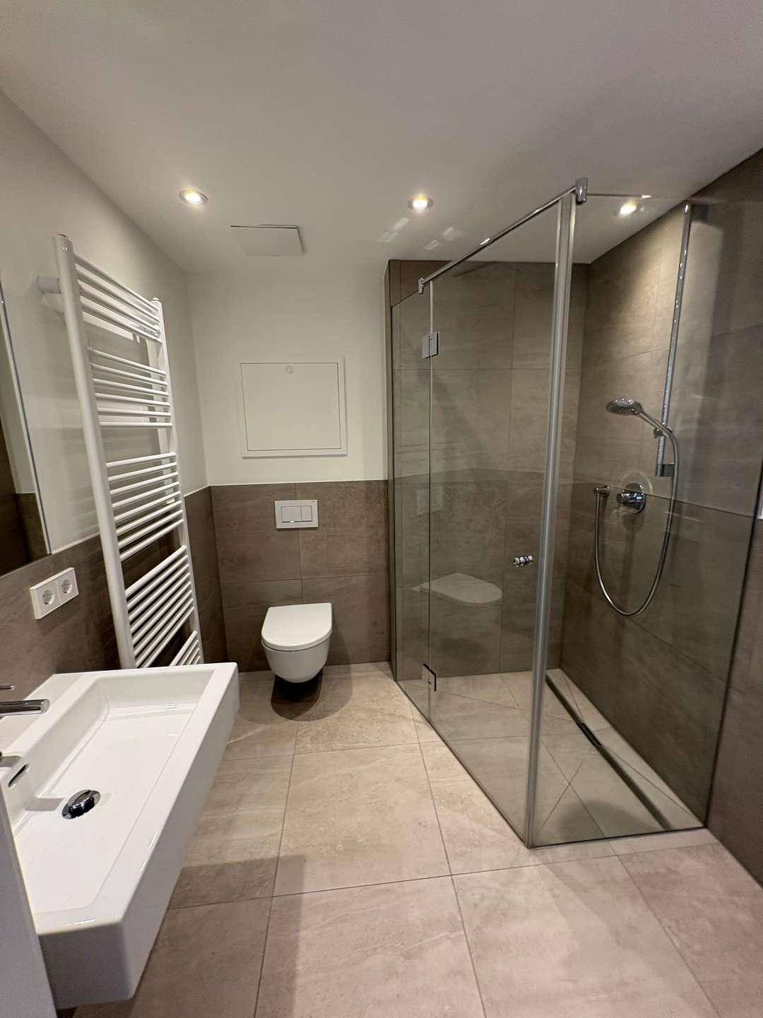 Modernes Badezimmer mit ebenerdiger Dusche, Wand-WC und beheiztem Handtuchhalter.