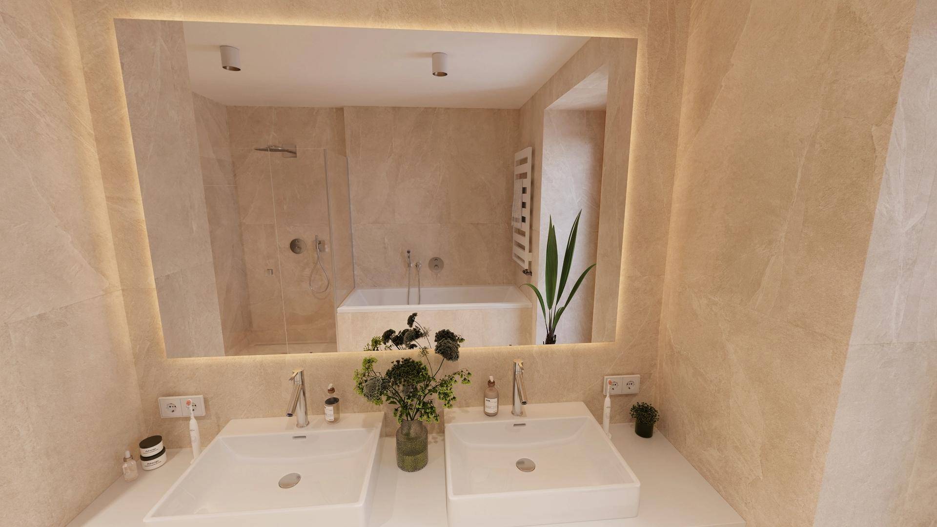 Modernes Badezimmer mit Doppelwaschbecken, beleuchtetem Spiegel und Badewanne im Hintergrund.