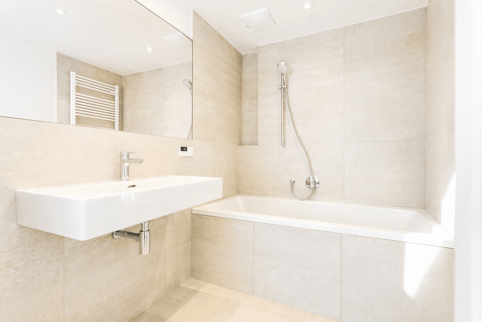 Modernes Badezimmer mit Badewanne, schwebendem Waschbecken und großem Spiegel.