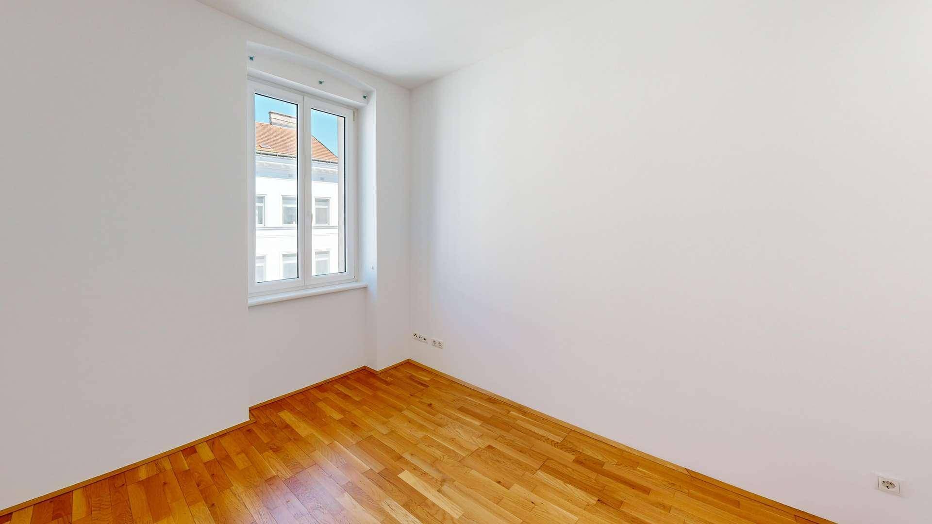 Schlichtes Zimmer mit Parkettboden und einem Fenster, ideal als Schlaf- oder Arbeitszimmer.