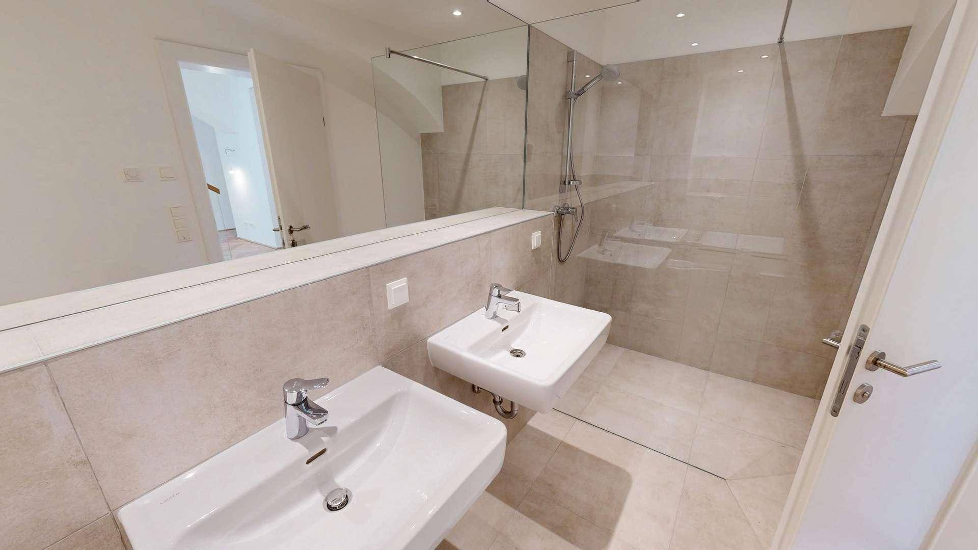 Modernes Badezimmer mit Doppelwaschbecken, großem Spiegel und begehbarer Dusche mit Glaswand.