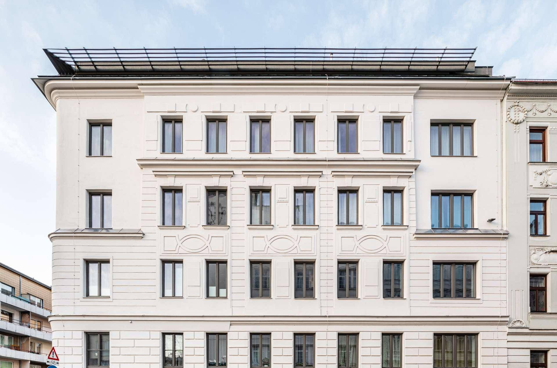 Klassische Fassade eines Mehrfamilienhauses mit vielen Fenstern und Solaranlage auf dem Dach.