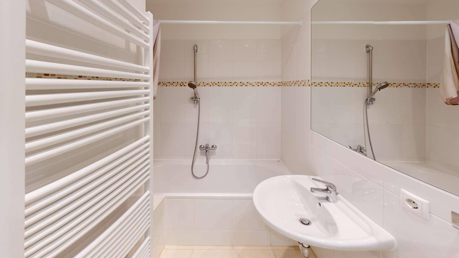 Funktionales Badezimmer mit Badewanne, Dusche, Einzelwaschbecken und beheiztem Handtuchhalter.