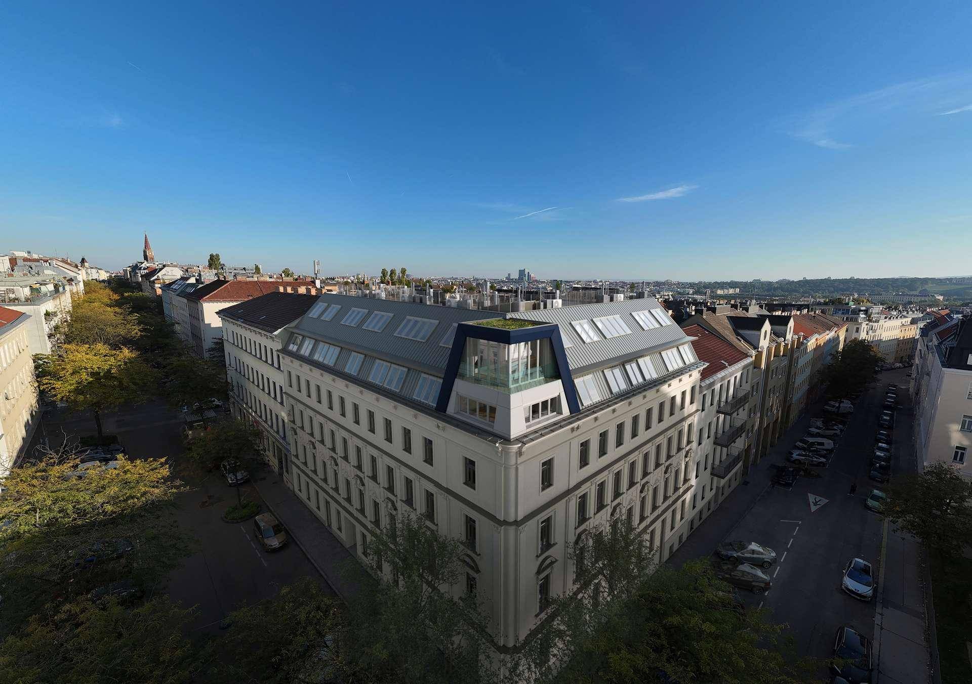 Luftaufnahme eines historischen Gebäudes mit modernem Dachausbau in städtischer Umgebung.
